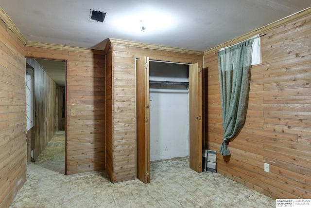 unfurnished bedroom with light carpet, a closet, and wood walls