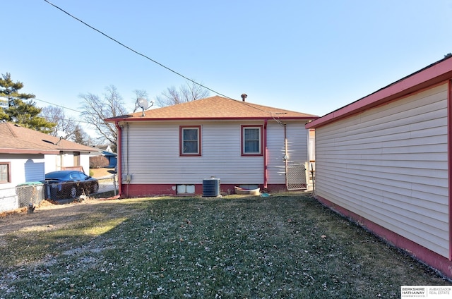 back of house with cooling unit and a lawn