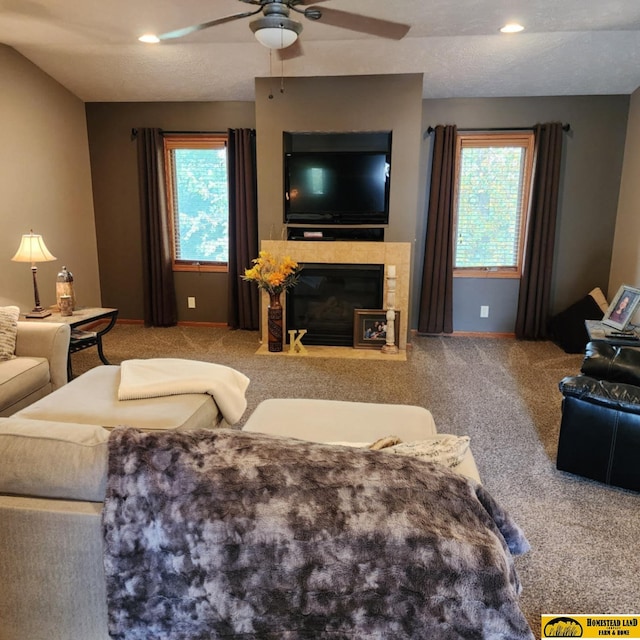 living room with ceiling fan, light colored carpet, a tiled fireplace, and a wealth of natural light