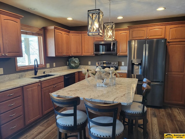 kitchen with stainless steel appliances, sink, dark wood-type flooring, a breakfast bar, and a center island