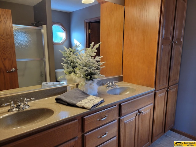 bathroom featuring toilet, tile patterned flooring, a shower with shower door, and vanity