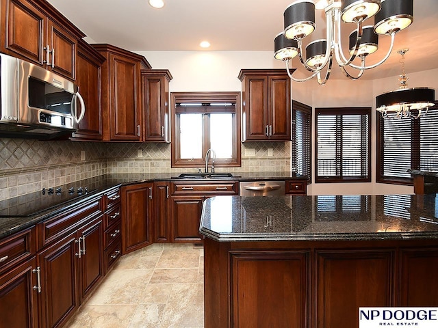 kitchen with sink, a chandelier, dark stone counters, and appliances with stainless steel finishes