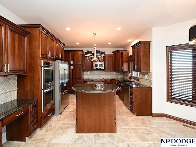 kitchen with a center island, decorative light fixtures, backsplash, appliances with stainless steel finishes, and sink