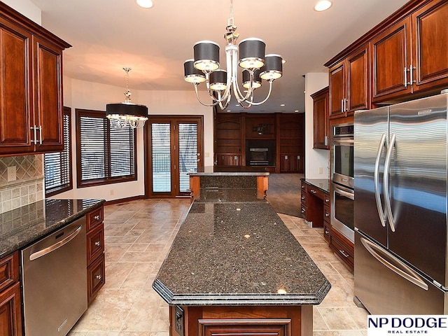 kitchen with a center island, a chandelier, dark stone counters, and appliances with stainless steel finishes