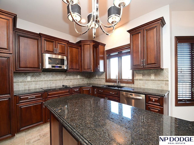 kitchen with decorative light fixtures, dark stone counters, appliances with stainless steel finishes, and sink