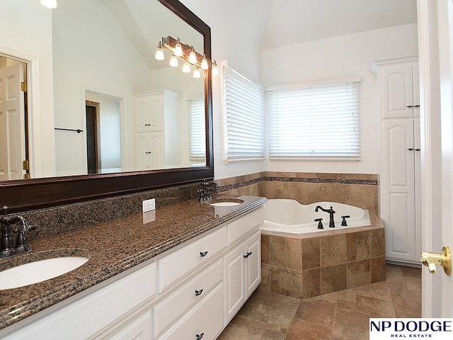 bathroom featuring lofted ceiling, tiled tub, and vanity