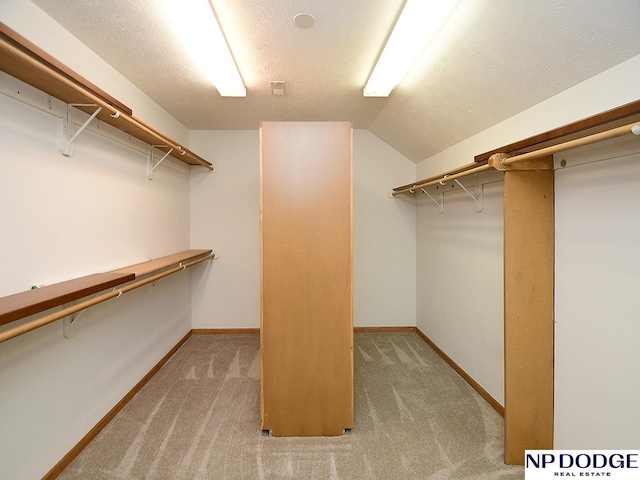 spacious closet featuring vaulted ceiling and light carpet