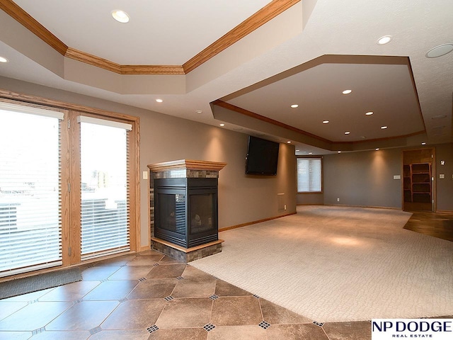 unfurnished living room with a multi sided fireplace, tile patterned flooring, ornamental molding, and a tray ceiling