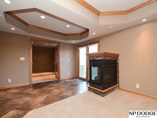 unfurnished living room with a multi sided fireplace, crown molding, dark carpet, and a tray ceiling