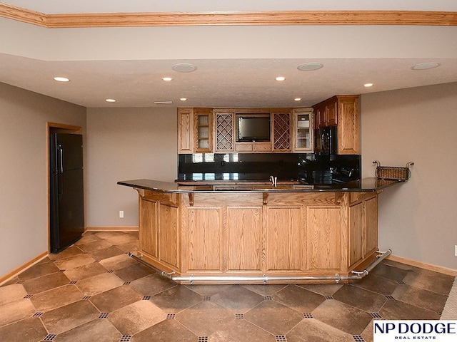 bar featuring black refrigerator, decorative backsplash, and ornamental molding