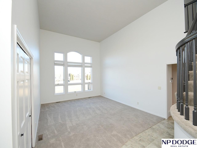 carpeted spare room featuring a towering ceiling