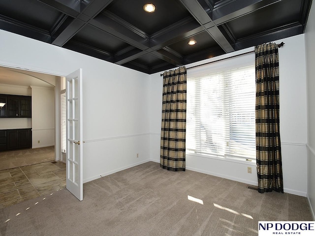 empty room with beamed ceiling, crown molding, coffered ceiling, and carpet