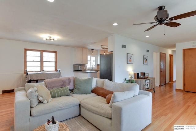 living room featuring ceiling fan, light wood-type flooring, and sink