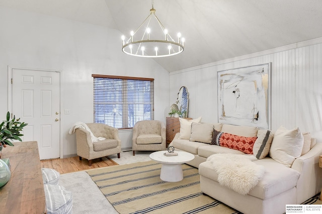 living room with lofted ceiling, an inviting chandelier, and light hardwood / wood-style floors