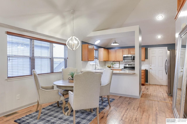 dining space featuring light hardwood / wood-style floors, sink, lofted ceiling, and a chandelier