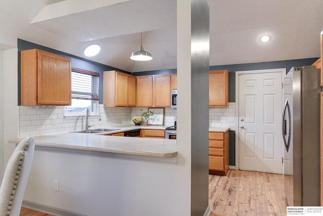 kitchen with light hardwood / wood-style floors, hanging light fixtures, appliances with stainless steel finishes, kitchen peninsula, and sink