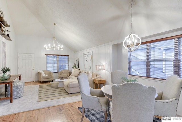 dining space with light hardwood / wood-style flooring, vaulted ceiling, and a chandelier