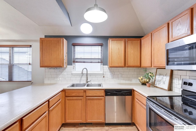 kitchen with stainless steel appliances, hanging light fixtures, a wealth of natural light, decorative backsplash, and sink