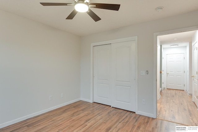 unfurnished bedroom with ceiling fan, light wood-type flooring, and a closet