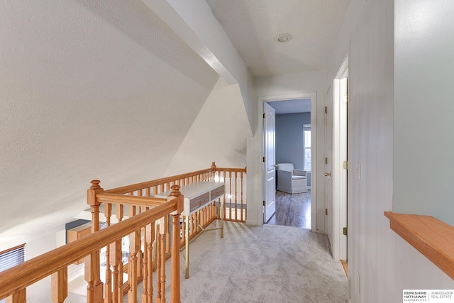 hallway with lofted ceiling and light colored carpet