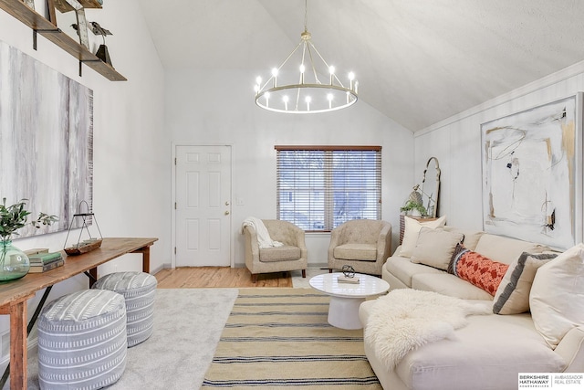 living room featuring lofted ceiling, an inviting chandelier, and light hardwood / wood-style flooring