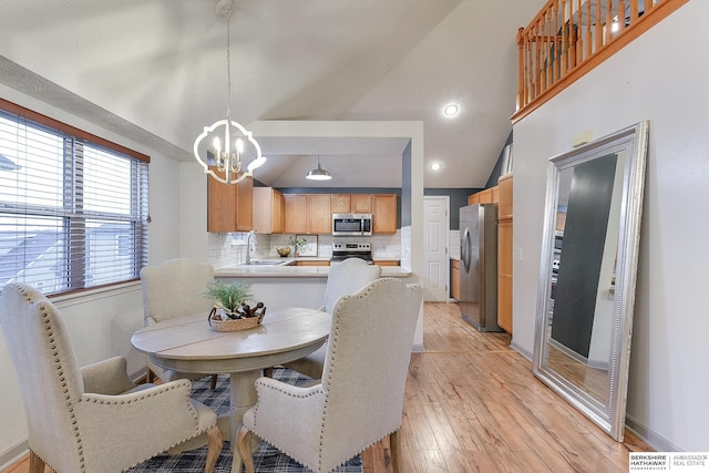 dining room featuring lofted ceiling, light wood-type flooring, and a notable chandelier