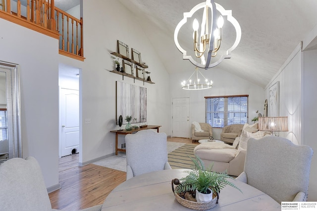 living room with a textured ceiling, light wood-type flooring, high vaulted ceiling, and a chandelier