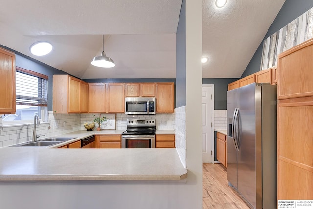 kitchen with stainless steel appliances, decorative light fixtures, sink, and vaulted ceiling