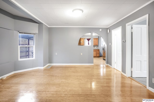 empty room with light wood-type flooring, crown molding, and plenty of natural light