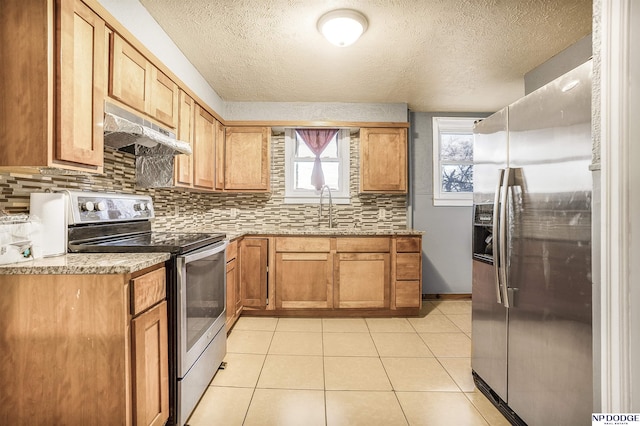 kitchen featuring stainless steel appliances, light tile patterned floors, a textured ceiling, sink, and backsplash