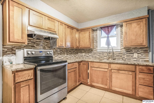 kitchen featuring light stone countertops, light tile patterned floors, sink, stainless steel range with electric cooktop, and backsplash