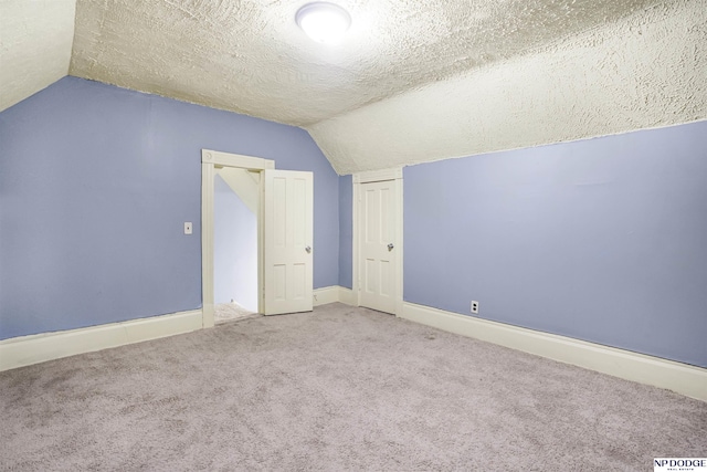 bonus room featuring a textured ceiling, vaulted ceiling, and carpet flooring