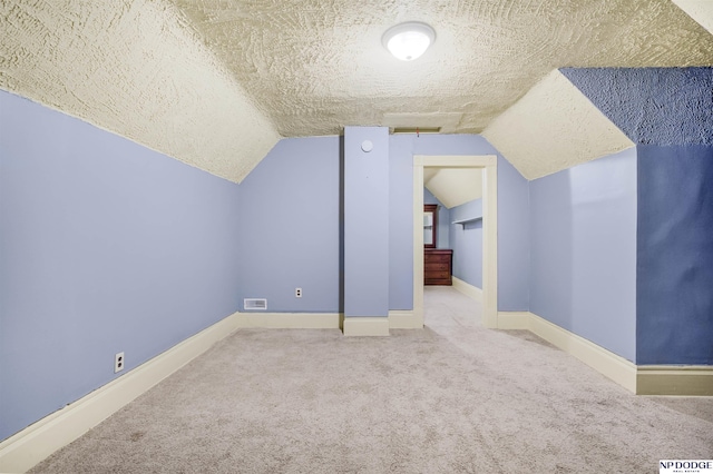 additional living space with a textured ceiling, carpet floors, and vaulted ceiling