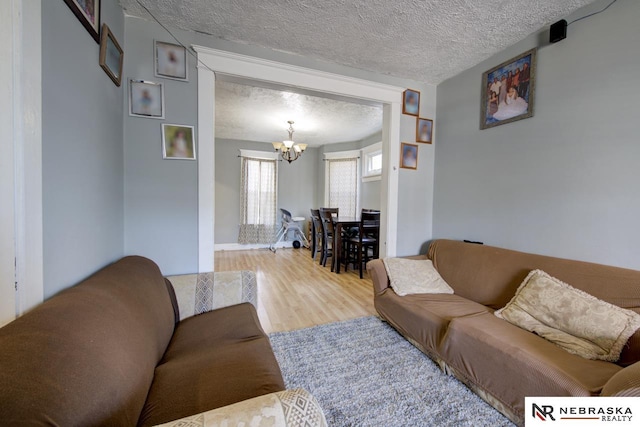 living room with an inviting chandelier, hardwood / wood-style floors, and a textured ceiling