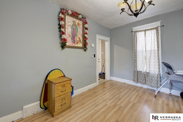 office with a textured ceiling, a notable chandelier, and light hardwood / wood-style floors