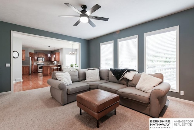 carpeted living room featuring ceiling fan with notable chandelier