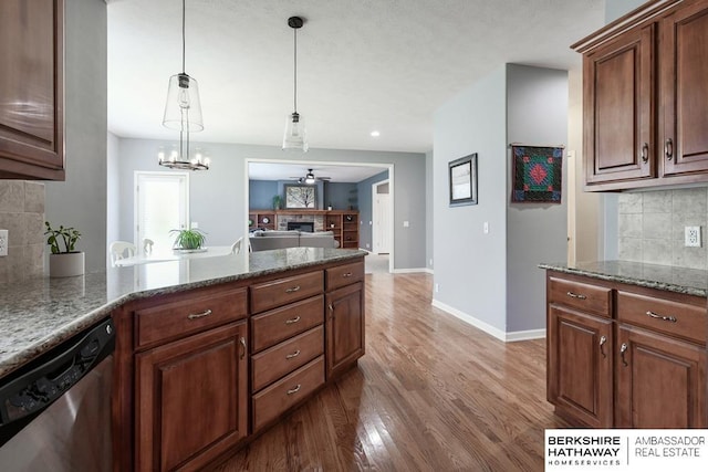 kitchen with dishwasher, dark stone countertops, wood-type flooring, decorative backsplash, and ceiling fan with notable chandelier