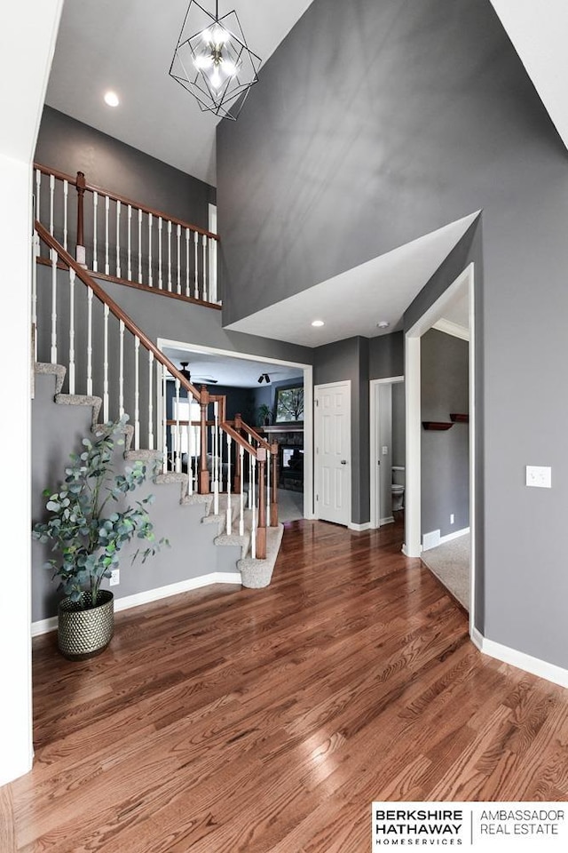 entrance foyer with a high ceiling, an inviting chandelier, and wood-type flooring