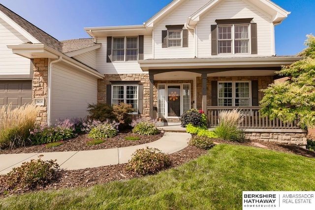 view of front of home with covered porch, a front yard, and a garage