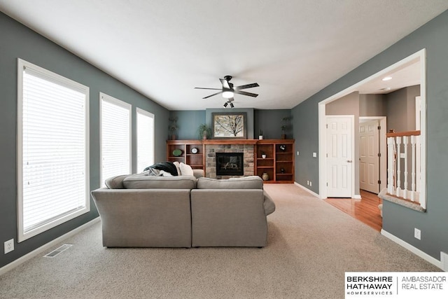 carpeted living room with a fireplace, ceiling fan, and a wealth of natural light