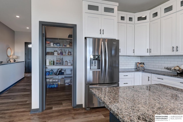 kitchen featuring dark hardwood / wood-style floors, stainless steel refrigerator with ice dispenser, white cabinetry, stone countertops, and backsplash