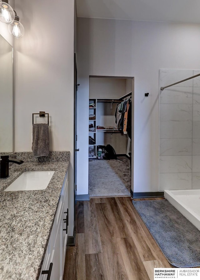 bathroom with hardwood / wood-style floors, walk in shower, and vanity