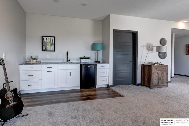 kitchen featuring white cabinets, fridge, dark colored carpet, and sink