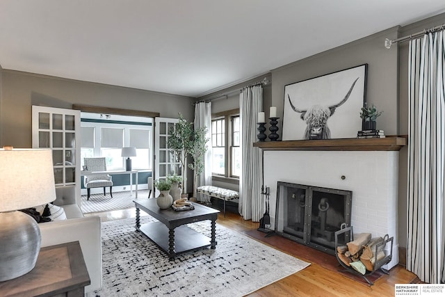 living room with a brick fireplace and hardwood / wood-style flooring