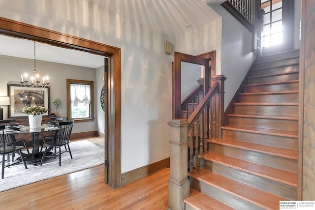 stairway featuring hardwood / wood-style flooring and an inviting chandelier