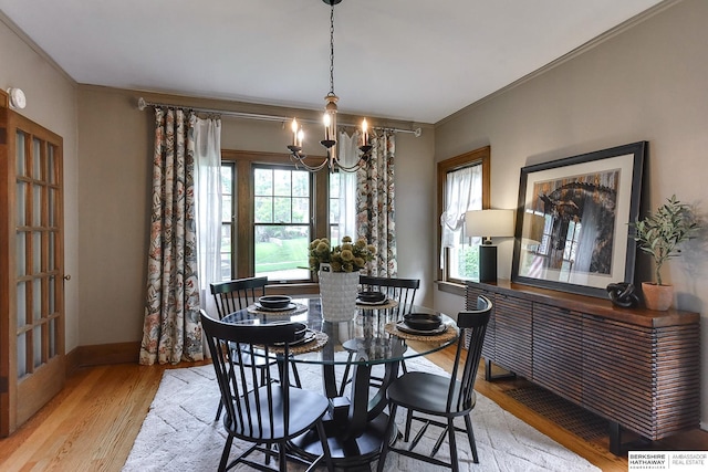 dining space featuring a notable chandelier, light hardwood / wood-style flooring, and crown molding