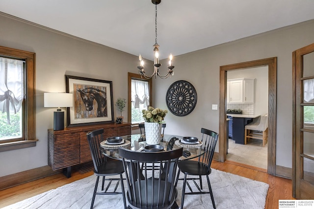 dining space with light hardwood / wood-style floors and a chandelier