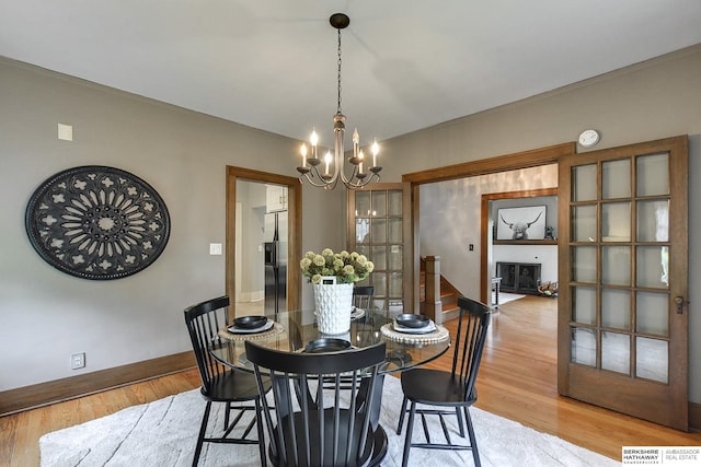 dining room with french doors, an inviting chandelier, and light wood-type flooring