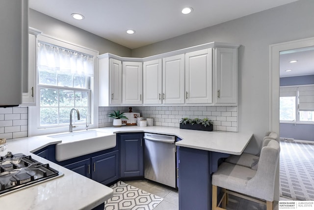 kitchen featuring dishwasher, blue cabinetry, sink, white cabinetry, and backsplash