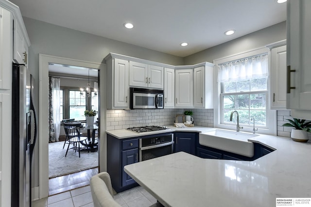 kitchen with white cabinets, appliances with stainless steel finishes, blue cabinetry, and sink